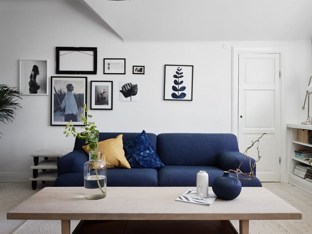 Синий диван на фоне белых стен гостиной