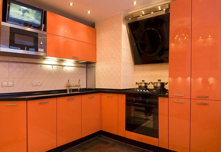 Зону фартука в оранжевой кухне можно отделать плиткой как темного, так и светлого оттенка