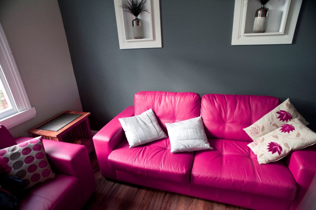 Контрастный кожаный диван розового цвета в интерьере комнаты