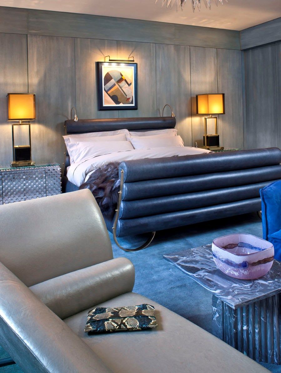 Синяя кожаная кровать в серо-синей спальне с бежевым потолком